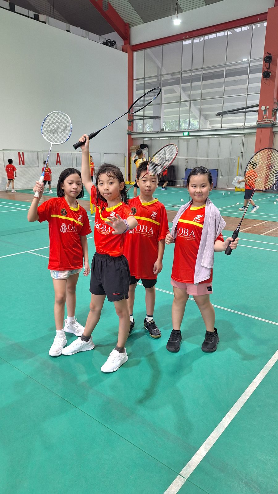Four campers in OBA jerseys posing with rackets raised