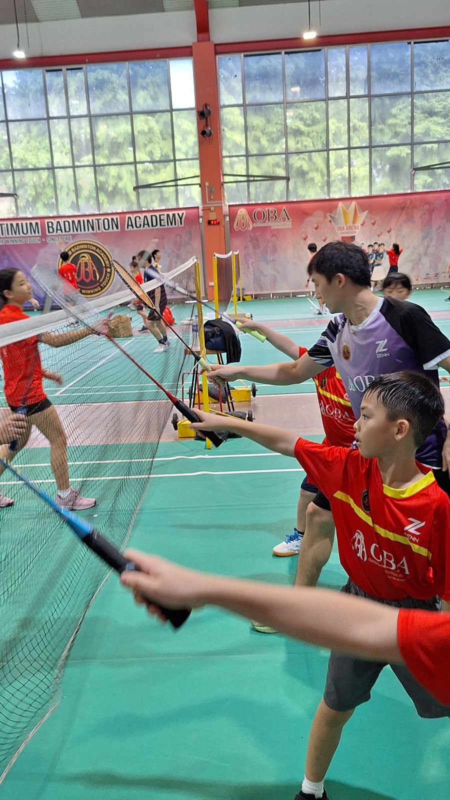 Coach and campers reaching over the net with their rackets