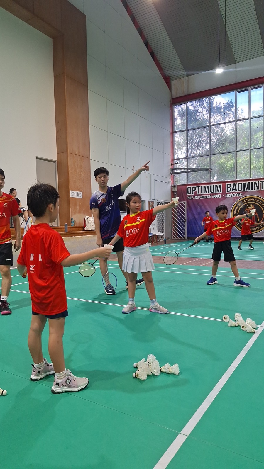 A coach directing a group of children through a drill on court