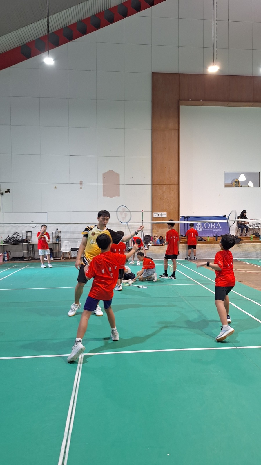 Children training across the courts of a full hall