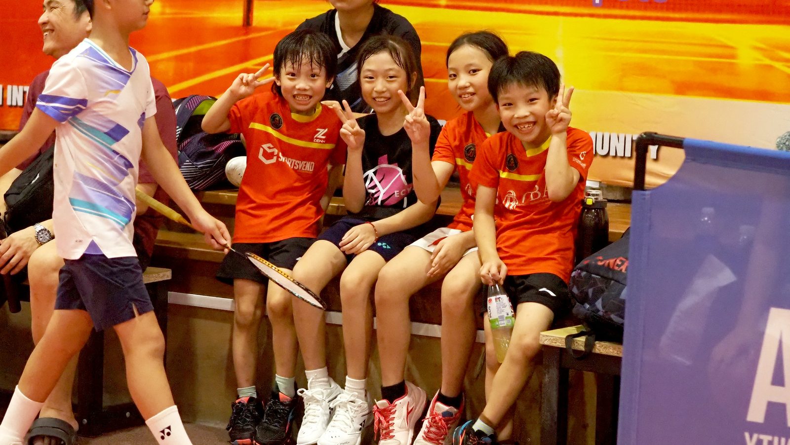Four juniors in OBA jerseys smiling together on the bench