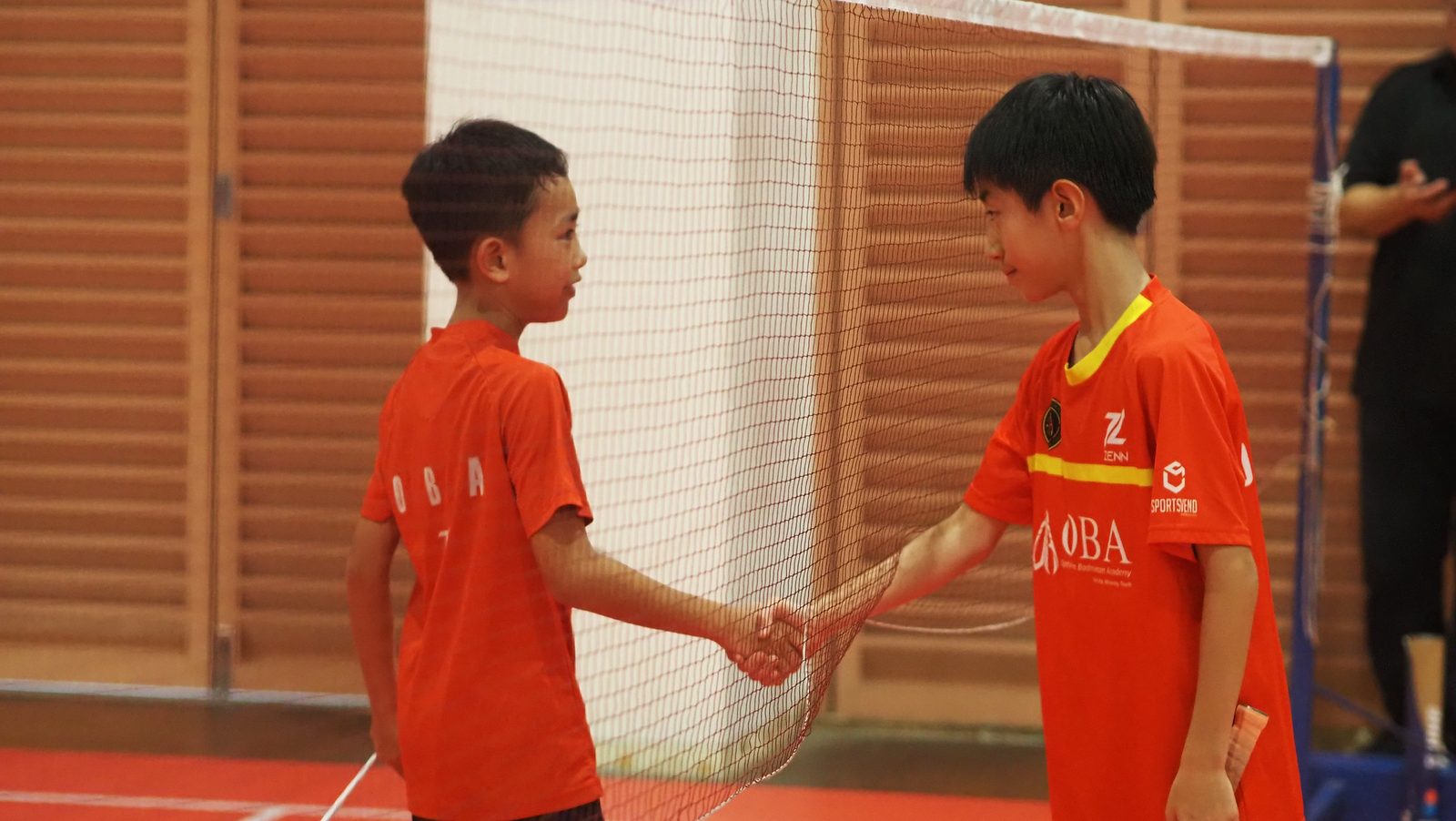 Two juniors shaking hands across the net